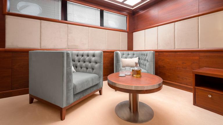 The seating area in the cabin consists of two designer armchairs and a round wooden table.